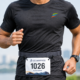 Adjustable Race Bib Holder Belt-4 Runner wearing a charcoal grey Race Bib Belt Pro with a race bib securely attached and elastic chambers positioned at the waist.